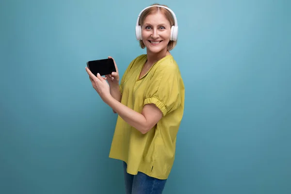 middle aged business. blond woman with headphones and a smartphone in her hands.