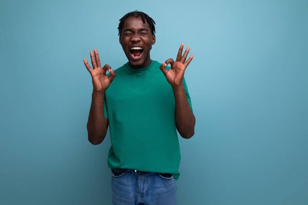 Смешной смеющийся американский молодой парень в футболке на синем фоне.