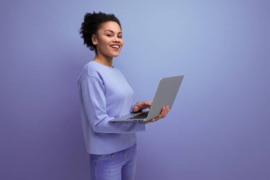 Başarılı genç afro saçlı esmer kadın dizüstü bilgisayar kullanıyor..