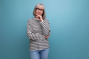 60 'lı yaşlarda hoş bir kadının parlak bir stüdyo arka planında şık bir portresi..