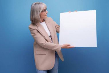 Kendine güvenen 60 'lı yaşlarda, ceketli orta yaşlı bir kadının yakın plan çekimi, fotokopi alanı olan parlak bir arka planda mokap şablonu gösteriyor..