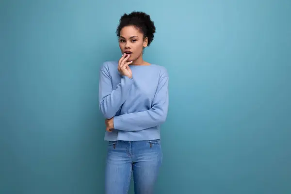 close-up of a young pensive dark-skinned woman with puffy hair in blue clothes isolated background with copy space.