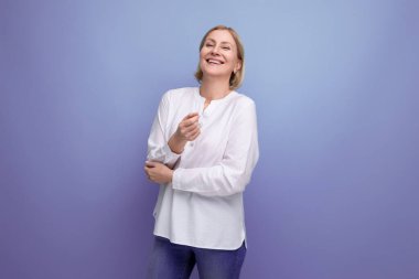 Stüdyo arka planında menopoza girmiş, 50 'li yaşlarda neşeli, sarışın bir kadın..