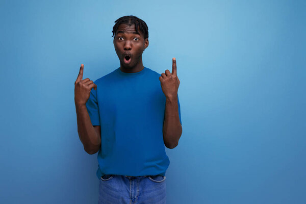 энергичный молодой черный американец указывает на стену на изолированном фоне.