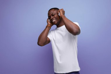 Beyaz tişörtlü, kısa saçlı, kulaklıkla müzik dinlemekten hoşlanan 30 'lu yılların sevimli Afrikalı erkeği..