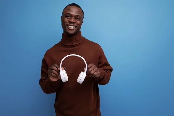 positive young African music maker with white headphones.