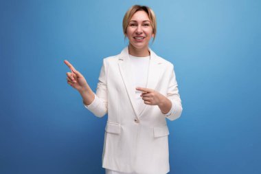Beyaz ceketli, zayıf, sarışın, iş adamı bir kadın, bir tarafı işaret ediyor..