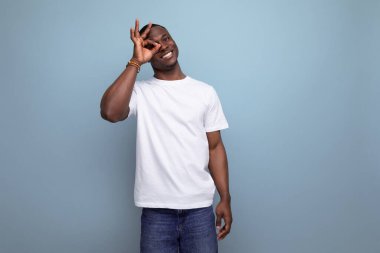 Beyaz tişörtlü koyu tenli, kendine güvenen Amerikalı bir adam..