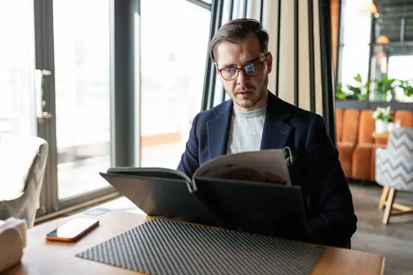 Stock image european man looks at the menu while sitting in a cafe.