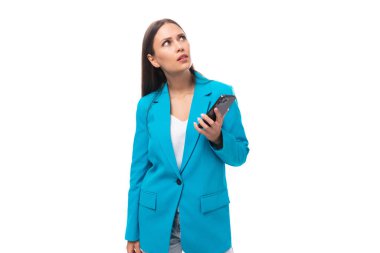 Şık bir iş ceketi giymiş genç esmer kadın elinde akıllı bir telefon tutuyor..