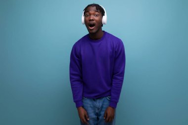 Mavi kazaklı Amerikalı genç adam kulaklıkla müzik dinliyor..