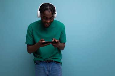 Genç Afrikalı adam kablosuz kulaklık ve cep telefonuyla video izliyor..