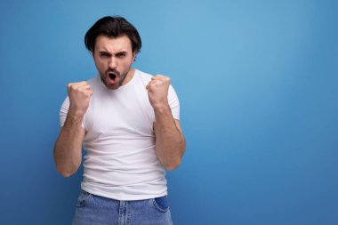 Beyaz tişörtlü, kot pantolonlu, esmer, kendine güvenen genç adam..