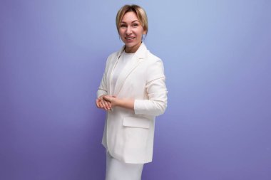 Ceket ve elbise giyen genç sarışın kadın mor arka planda, fotokopi alanı ile güven içinde poz veriyor..