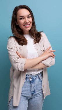 Esmer, genç, esmer bir bayan. Sıradan giyinmiş. Mavi arka planda gülümsüyor..