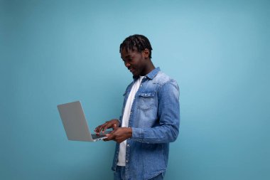 Kot ceketli kıvırcık saçlı, dizüstü bilgisayarı olan yakışıklı bir Afrikalı..