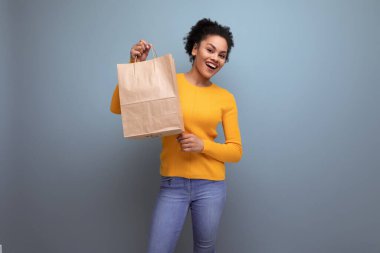 Güzel, 20 'li yaşlarda, siyah saçlı, sıradan sarı kazaklı, kahverengi çantalı Latin bir kadın..