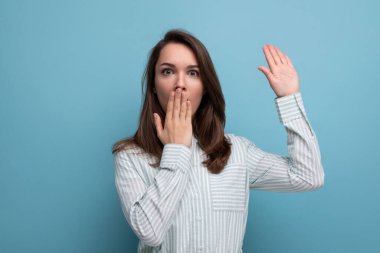 25 yaşında, kahverengi saçlı bir kadın elini kaldırıp ağzını kapatmak için yardım istiyor..