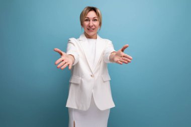 Güzel, ince, sarışın, beyaz ceketli genç bir iş kadını sarılmak için avuçlarını çekiyor..
