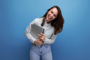 IT uzmanı 25 yaşında, kot ve tişörtlü esmer bir kadın elinde dizüstü bilgisayarla serbest çalışmayı seviyor..