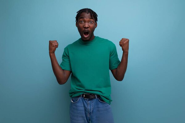 уверенная брюнетка модель стильный темнокожий мужчина в дредах в прохладной футболке на синем фоне.