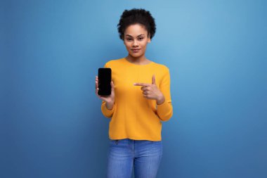 Hoş 20 'li yaşlarda, beyaz saçlı, sıradan sarı bluzlu, akıllı telefon ekranı gösteren Latin bir kadın..