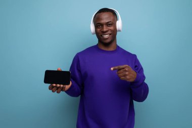 Arka planda mavi eşofmanlı ve fotokopi alanı olan yakışıklı Afrikalı genç adam..