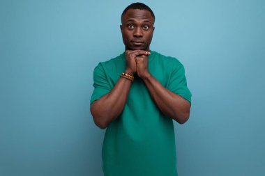 Tişört giymiş, kollarını kavuşturmuş genç, yakışıklı Afrikalı bir adam..