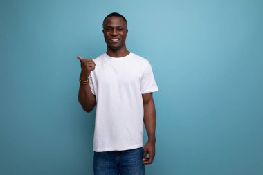 Beyaz tişörtlü, kısa saçlı, yakışıklı, 30 'lu yaşlarda Afrikalı bir adam elini uzaya uzatıyor..