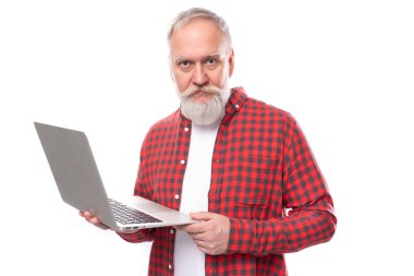 Orta yaş işi. Kendine güveni tam, beyaz saçlı, sakallı, laptoplu bir adam..