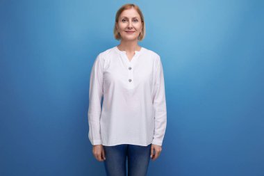 Beyaz bluzlu, ince, sarışın, orta yaşlı bir kadın..