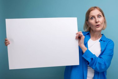Orta yaş iş konsepti. Orta yaşlı bir kadın elinde mavi arkaplan fotokopi alanı üzerinde mocap olan notlar için bir poster tutuyor..