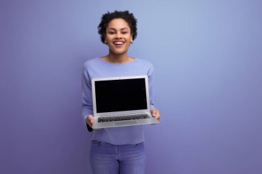 Dizüstü bilgisayarı olan başarılı bir afro-esmer kız öğrenci reklam için bir model sunuyor..