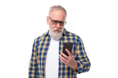 Bıyıklı, sakallı, olgun, gri saçlı emekli adam. Beyaz arka planda akıllı telefon teknolojisi..