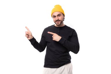 30 yaşında, siyah ceketli ve sarı şapkalı yakışıklı bir adam eliyle duvarı işaret ediyor..