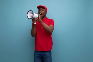 Kırmızı tişörtlü ve beyzbol şapkalı Amerikalı genç teslimatçı hoparlöre bağırıyor..