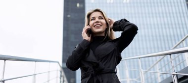 Kadın mimar sokakta telefonda bir nesneyi tartışıyor..