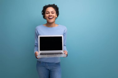 Dizüstü bilgisayarı olan başarılı bir afro-esmer kız öğrenci reklam için bir model sunuyor..