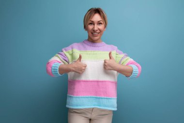 Çizgili süveter giyen sevimli sarışın kadın mavi arka planda fotokopi aletiyle süper jest yapıyor..