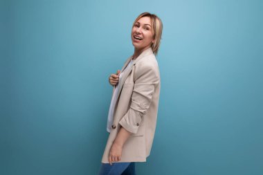 Stüdyonun arka planında beyaz saçlı, iş kıyafetli bir kadının portresi..