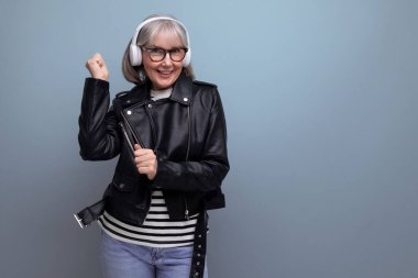 Modern 60 'ların modern modern, yaşlı, gri saçlı büyükannesi müzik dinliyor. Parlak bir arka planda..