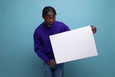 Mavi kazaklı Afrikalı genç adam elinde maketi olan bir poster tutuyor..