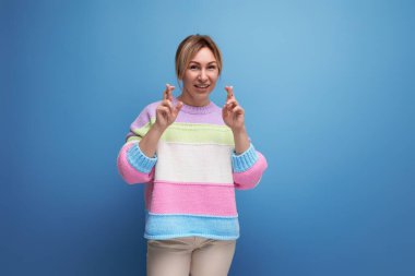 Sıradan görünüşlü hoş sarışın kadın. Mavi arka planda fotokopi alanı ile gülümsüyor..
