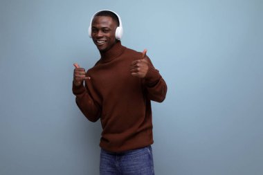 Yakışıklı, enerjik, Afrikalı bir adam. Arka planda kulaklık ve fotokopi alanı olan müzik dinliyor..