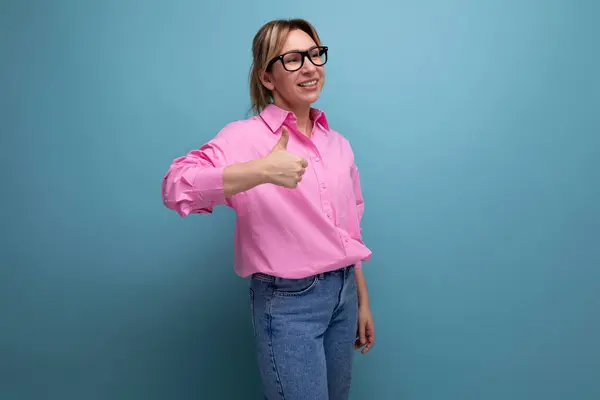 young successful caucasian blond office worker woman dressed in a pink shirt and jeans and glasses with a ponytail hairstyle got a promotion at work and rejoices.