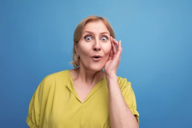 Şaşırmış orta yaşlı, kısa saçlı sarışın kadının portresi..