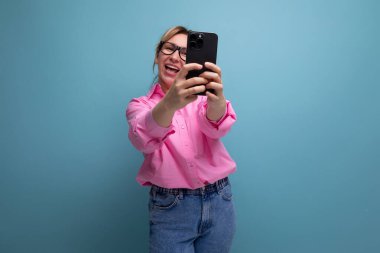 Pembe gömlekli, şık sarışın iş kadını telefonda selfie çekiyor..