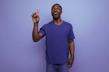 Çekici 25 'li yaşlarda, sıradan mavi tişörtlü Afrikalı bir adam parmağını kenarı işaret ediyor..