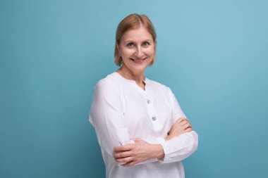 Beyaz bluzlu, esnek tenli, sarışın, 50 'li yaşlarda bir kadın..