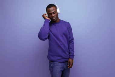 Mavi tişörtlü yakışıklı Afrikalı genç kulaklıkla müzik dinliyor..